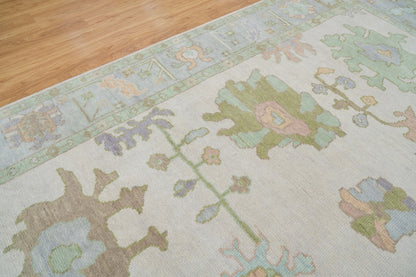 Close-up of pastel floral rug showing sage green, dusty blue, pink and beige botanical motifs.