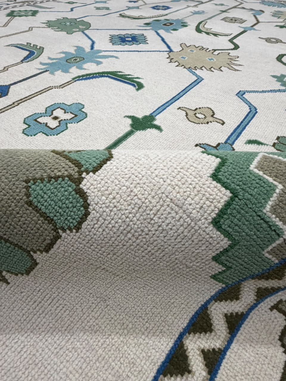 Close-up of the textured surface and colored pattern of an ivory wool rug.