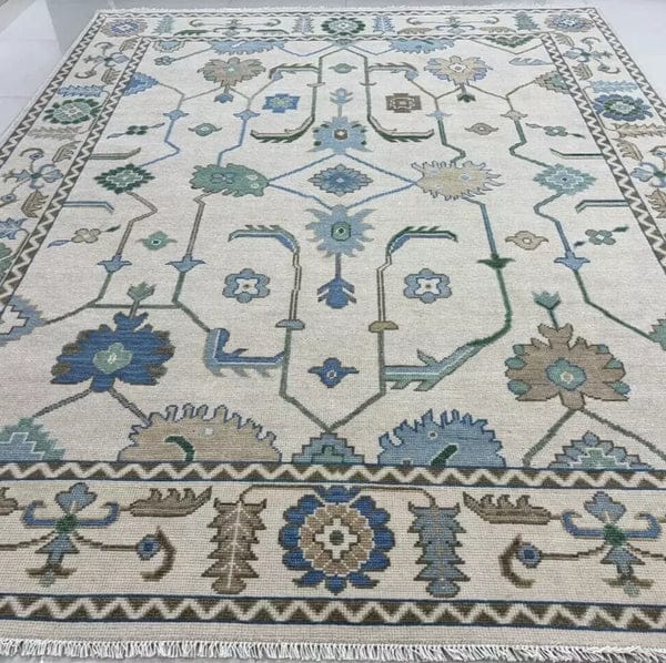 Large handmade ivory and blue vintage Oushak style area rug with floral border and neutral color palette.