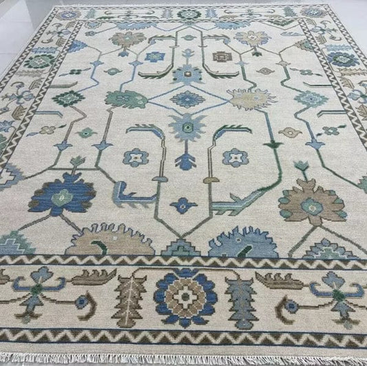 Large handmade ivory and blue vintage Oushak style area rug with floral border and neutral color palette.