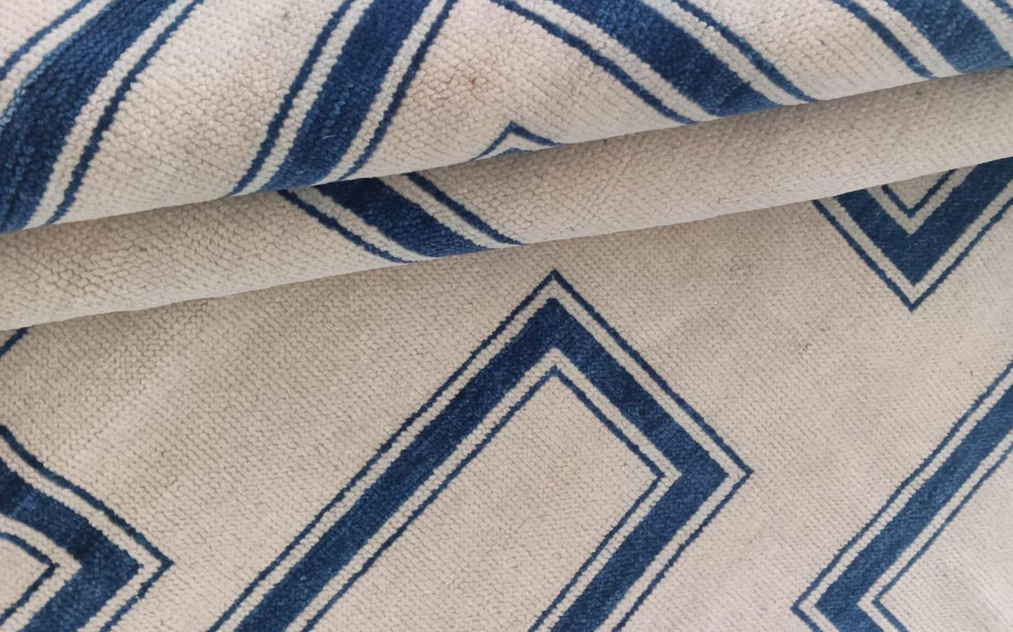 Close-up of modern geometric flatweave wool rug with indigo blue lines on ivory base