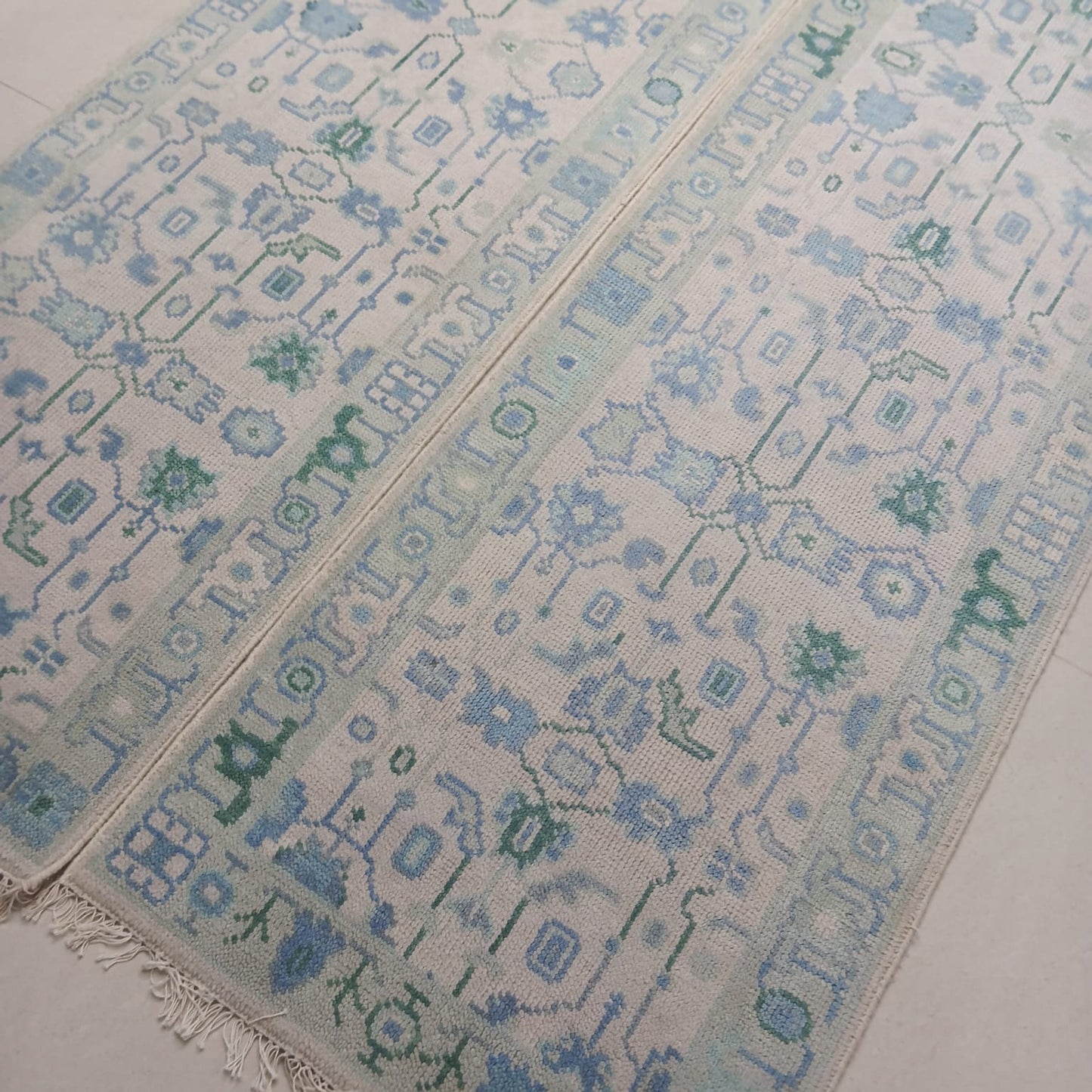 Modern tribal wool runner rug in blue and green tones shown at an angle