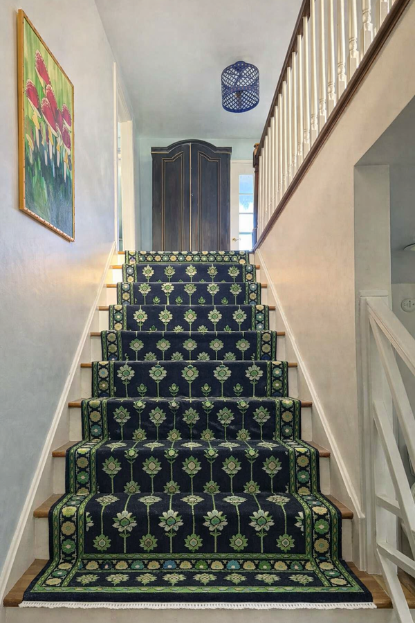 Handmade navy blue floral stair runner rug with traditional patterns installed on modern wooden staircase