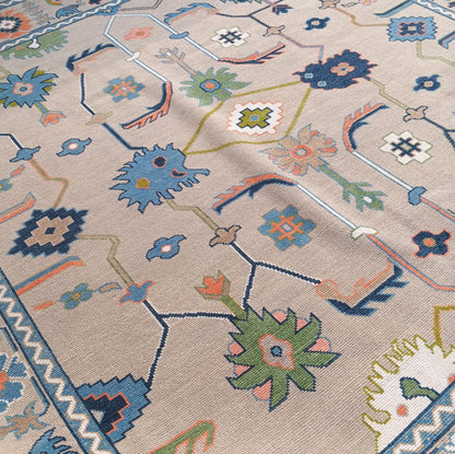 Close-up of handmade neutral vintage Oushak rug displaying beige field, navy, sage green and coral floral motifs.
