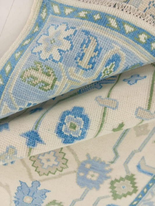 Detailed border of Oushak wool rug with blue and sage geometric accents