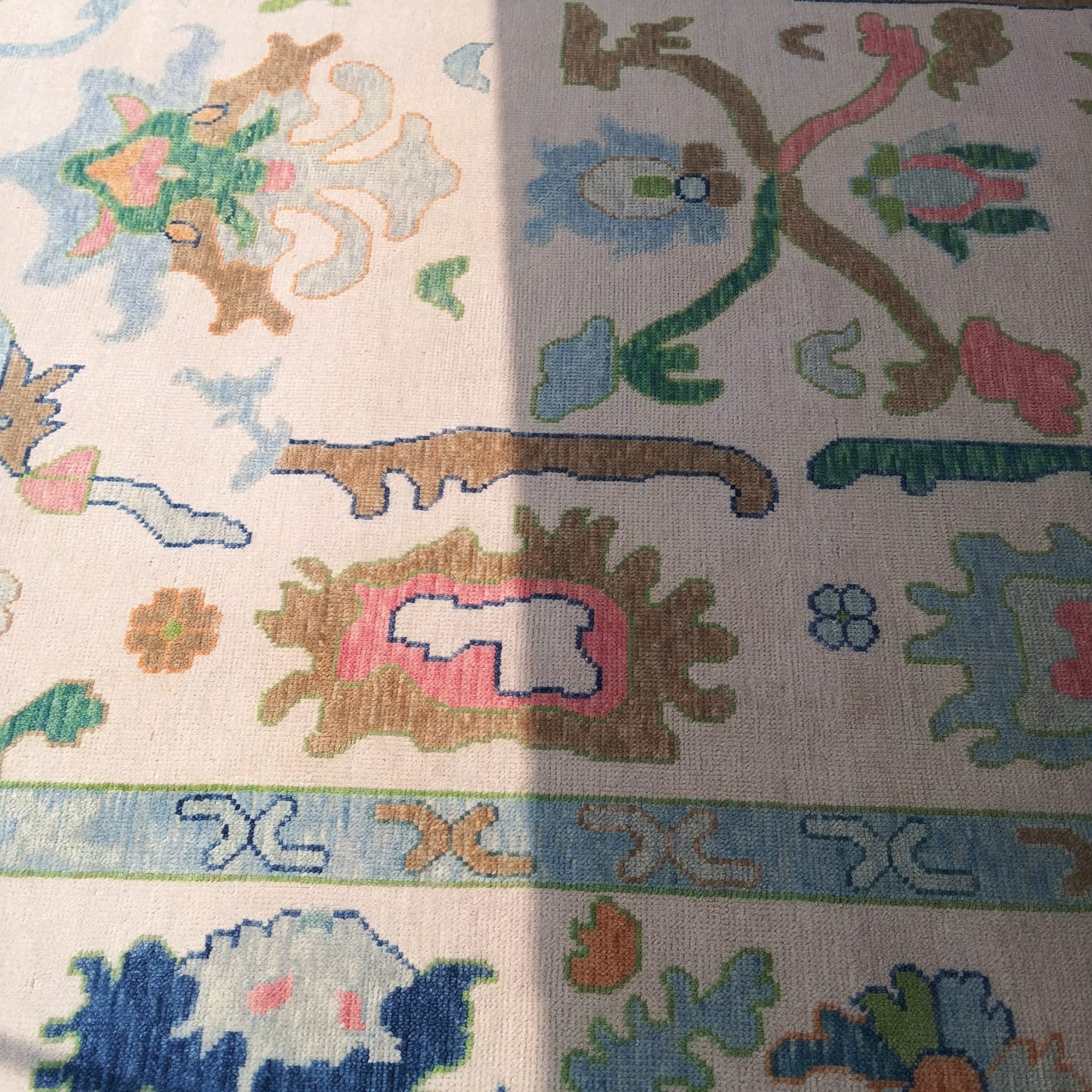 Close-up of Oushak rug border with blue green and pastel floral patterns