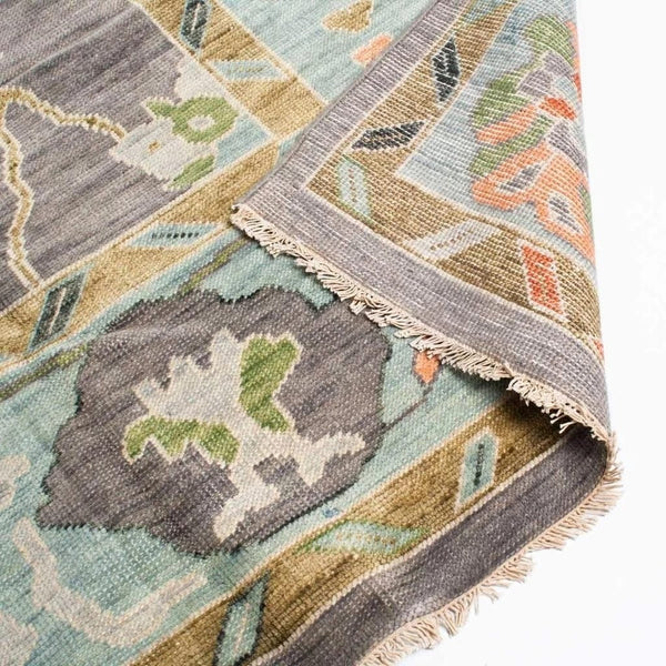 Hand-knotted Oushak rug care detail showing wool fringes and finely finished edges