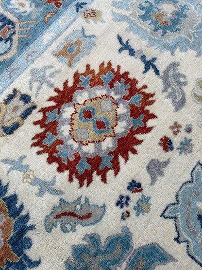 Close up of handmade Oushak rug featuring intricate floral medallion pattern in ivory blue and rust tones
