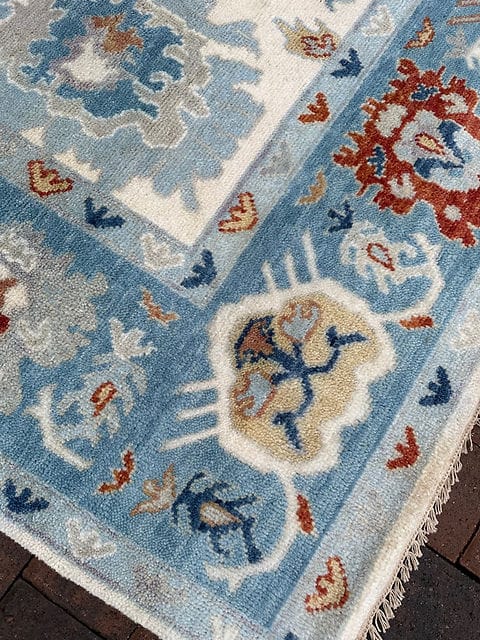 Corner detail of handmade Oushak rug with decorative floral border and ivory field