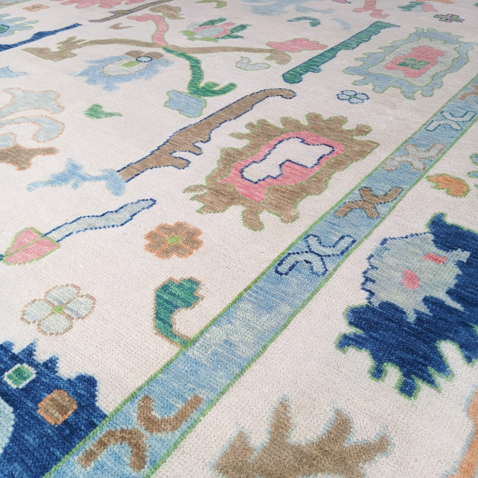 Floral motif detail of pastel Oushak rug with blue green and ivory tones