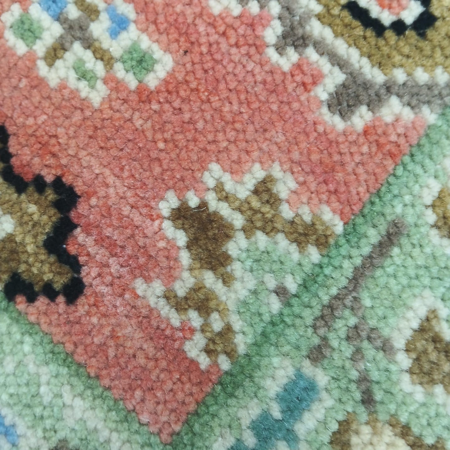 Close-up of handwoven Oushak rug showing floral Anatolian motifs in wool texture