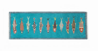Horizontal view of artisan handmade fish runner rug with turquoise base and colorful coastal fish designs