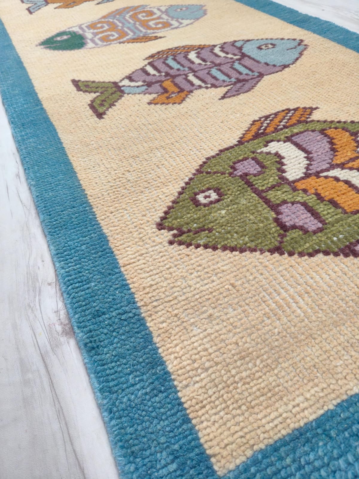 Close-up of Oushakaura coastal fish runner rug showing handmade woven texture and tassel fringe