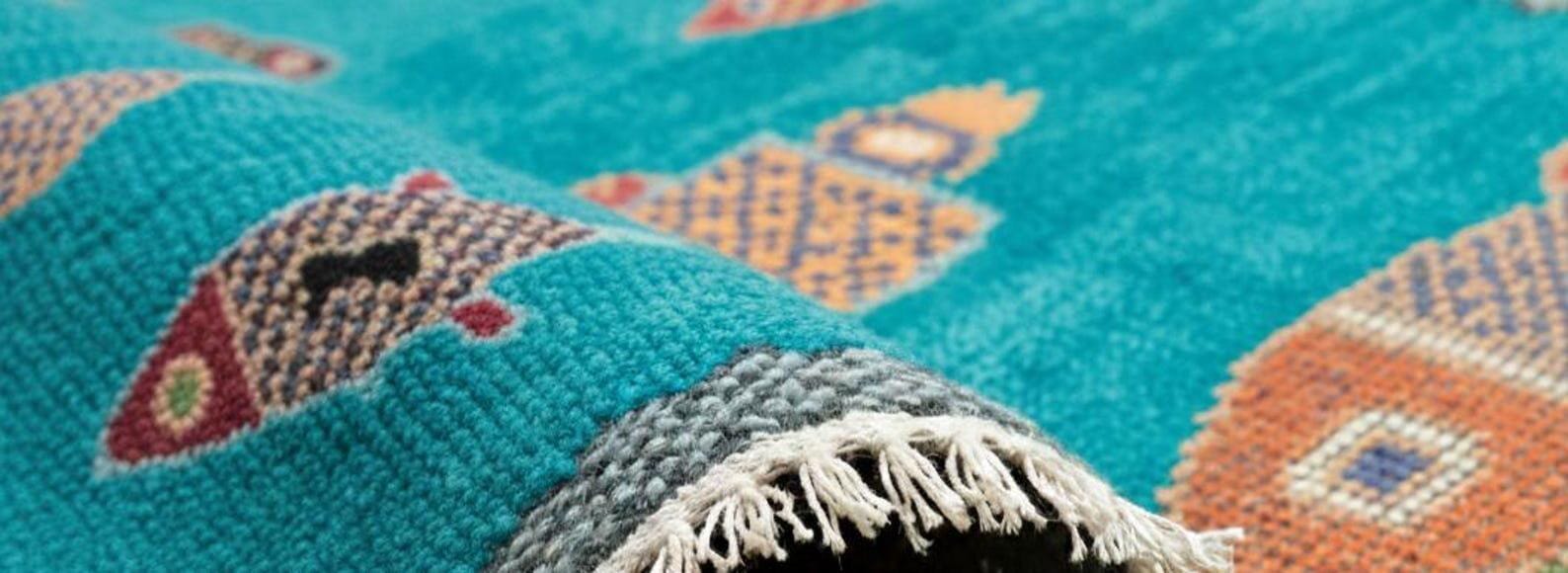 Closeup of handmade turquoise fish runner rug by Oushakaura featuring woven coastal fish motifs and artisan texture