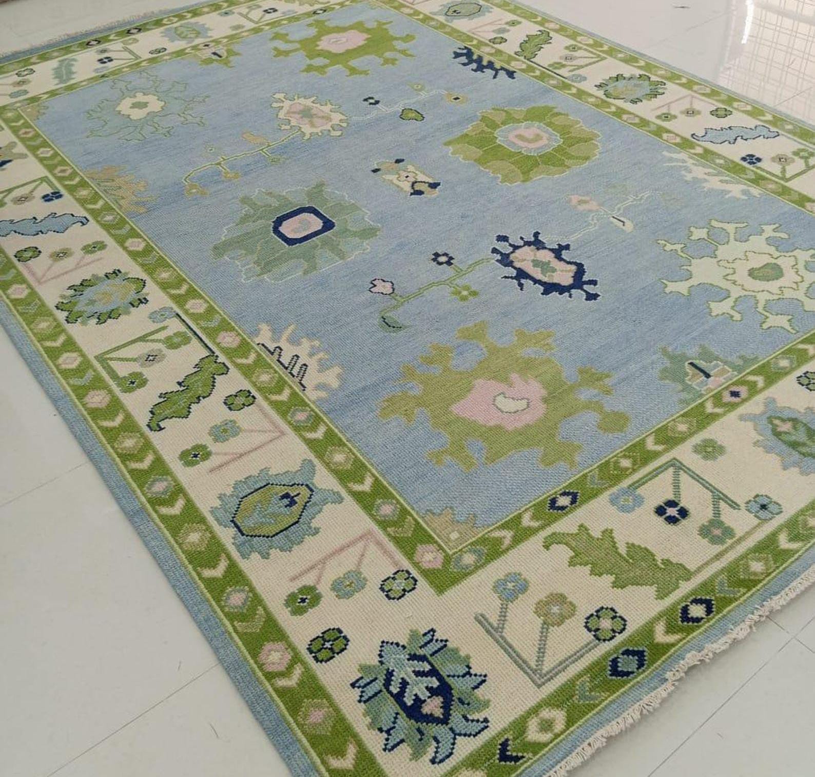 Handwoven Oushak wool area rug in pastel blue with olive green border