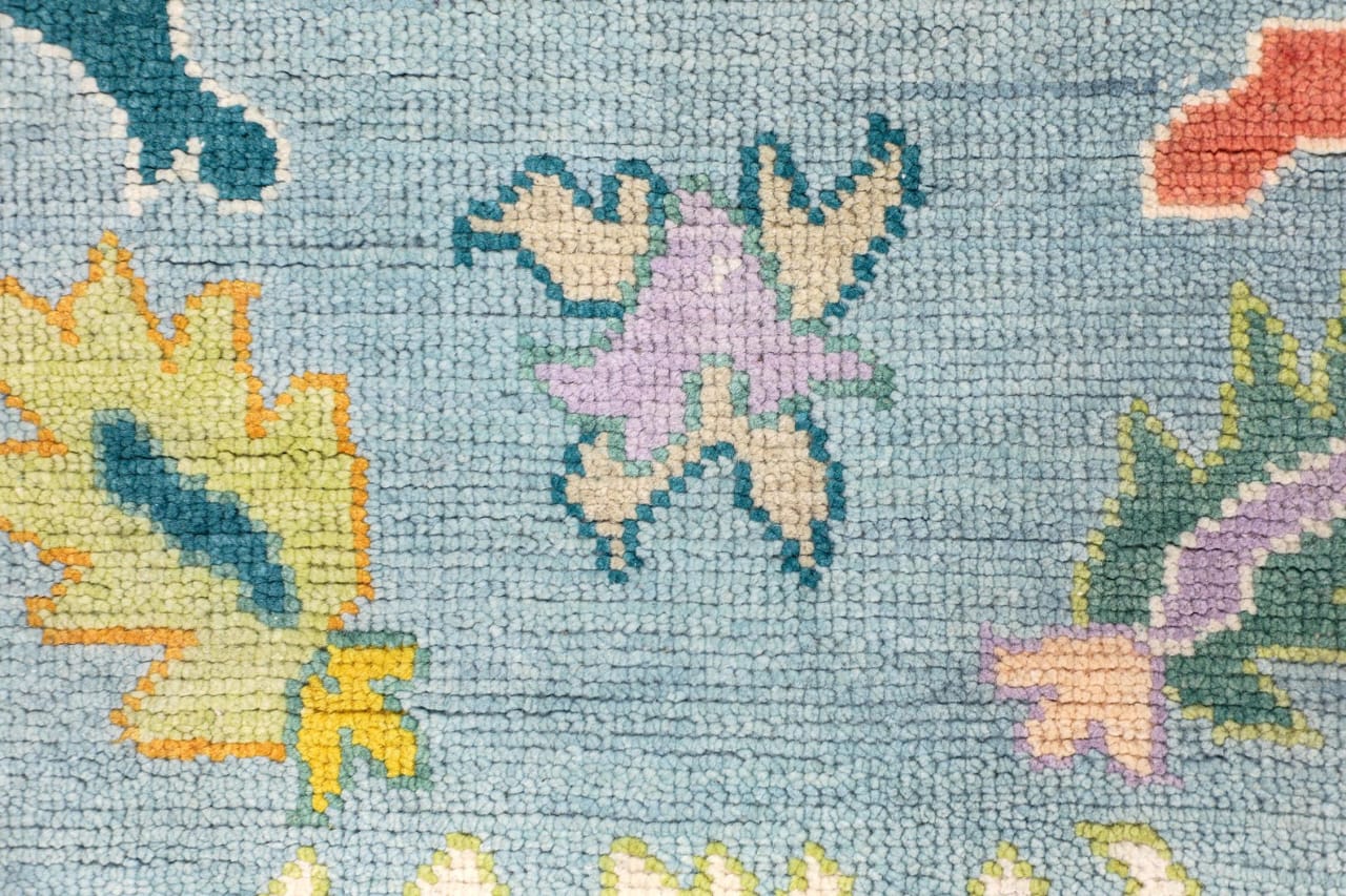 Close up of colorful floral pattern on pastel blue Oushak rug