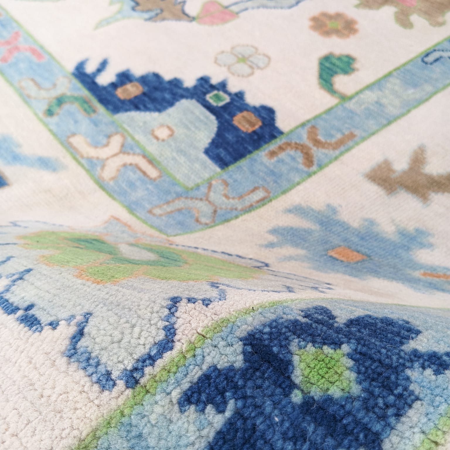 Angled pattern view of pastel blue Oushak rug with soft traditional motifs