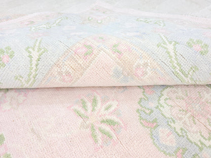 Pastel floral area rug showing low-pile woven texture and soft pink botanical design