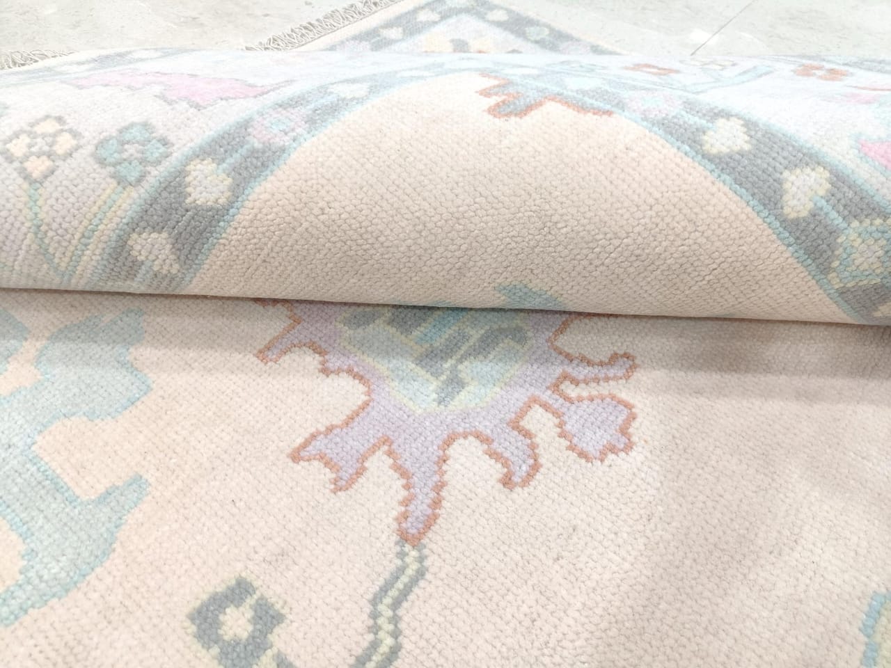 Close up of pastel floral medallion on ivory wool rug