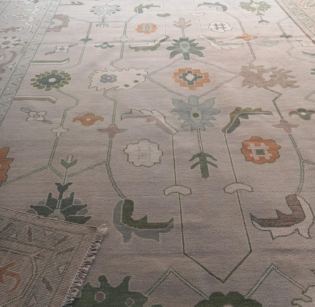 Close up of sage green and blue Oushak floral rug pattern