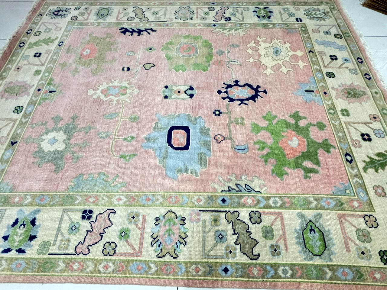 Traditional center floral motifs on handmade pastel pink Oushak wool rug