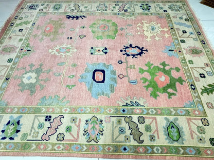 Traditional center floral motifs on handmade pastel pink Oushak wool rug