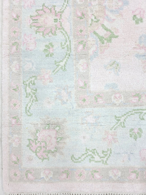 Pastel pink vintage floral rug showing delicate botanical motifs and decorative border