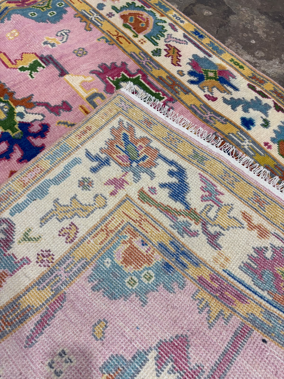 backside of a hand-knotted pink floral wool rug showing its construction