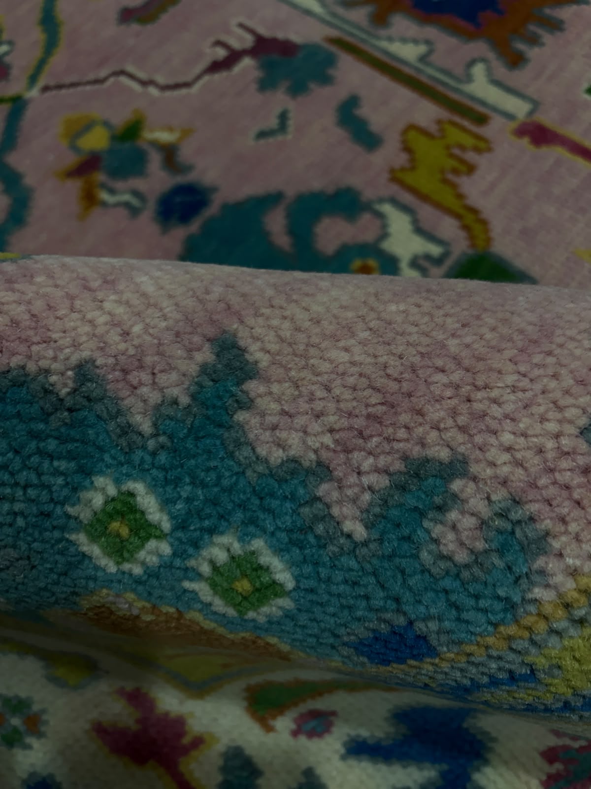 Close-up of the medium pile texture and pink floral design of a wool rug