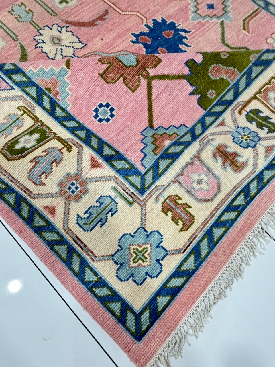 Corner detail of handmade blush pink vintage Turkish style rug.