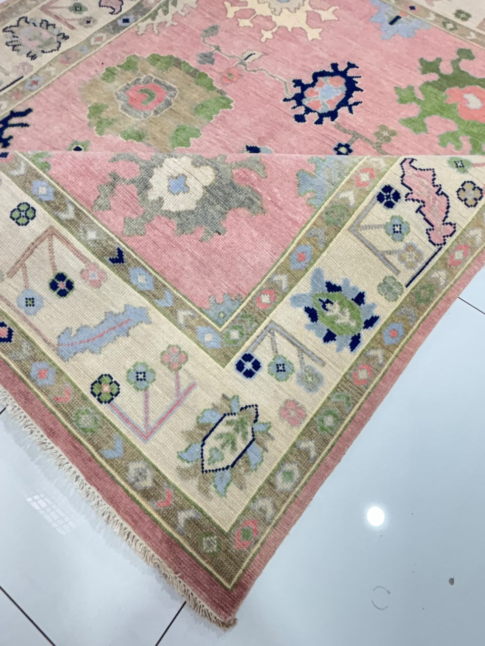 Close-up of floral border on handmade blush pink Oushak wool rug