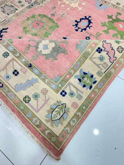 Close-up of floral border on handmade blush pink Oushak wool rug