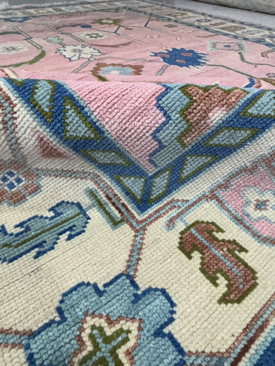 Pink folded close up Woven texture and floral pattern of an Oushak rug