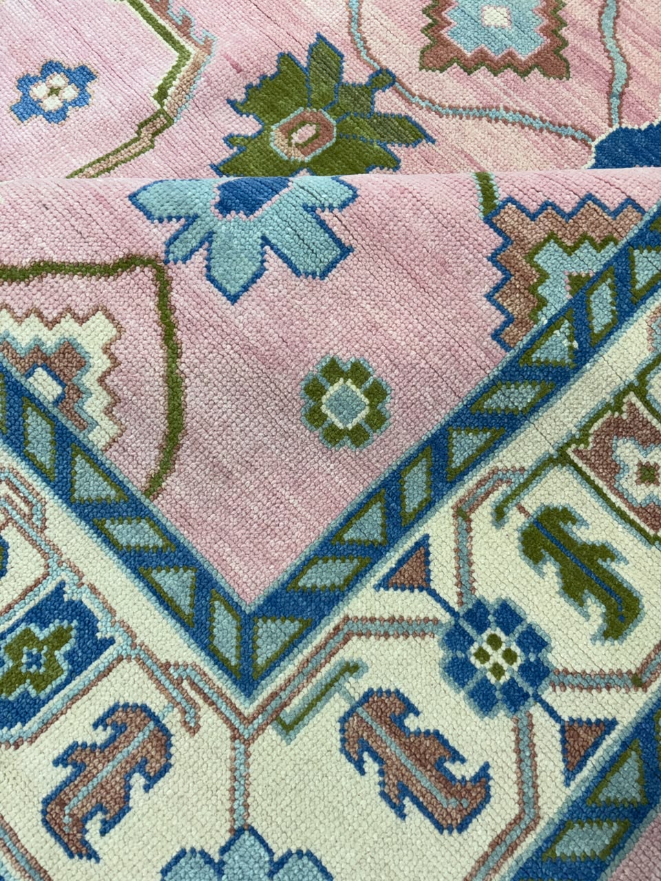 Close-up texture of handmade blush pink wool Oushak rug.