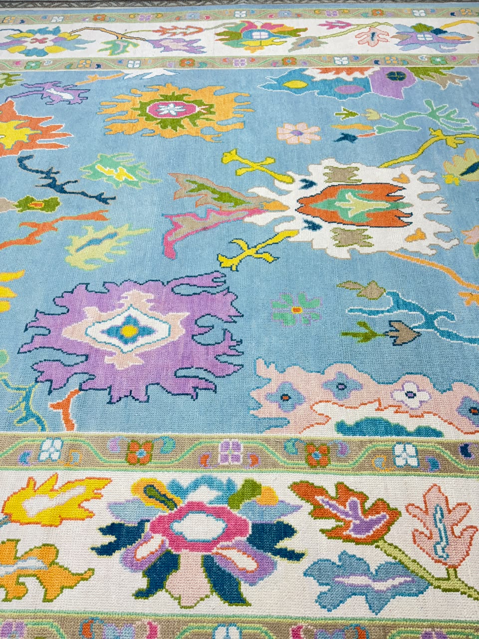 Detailed texture of premium handmade wool Oushak rug with colorful botanical design