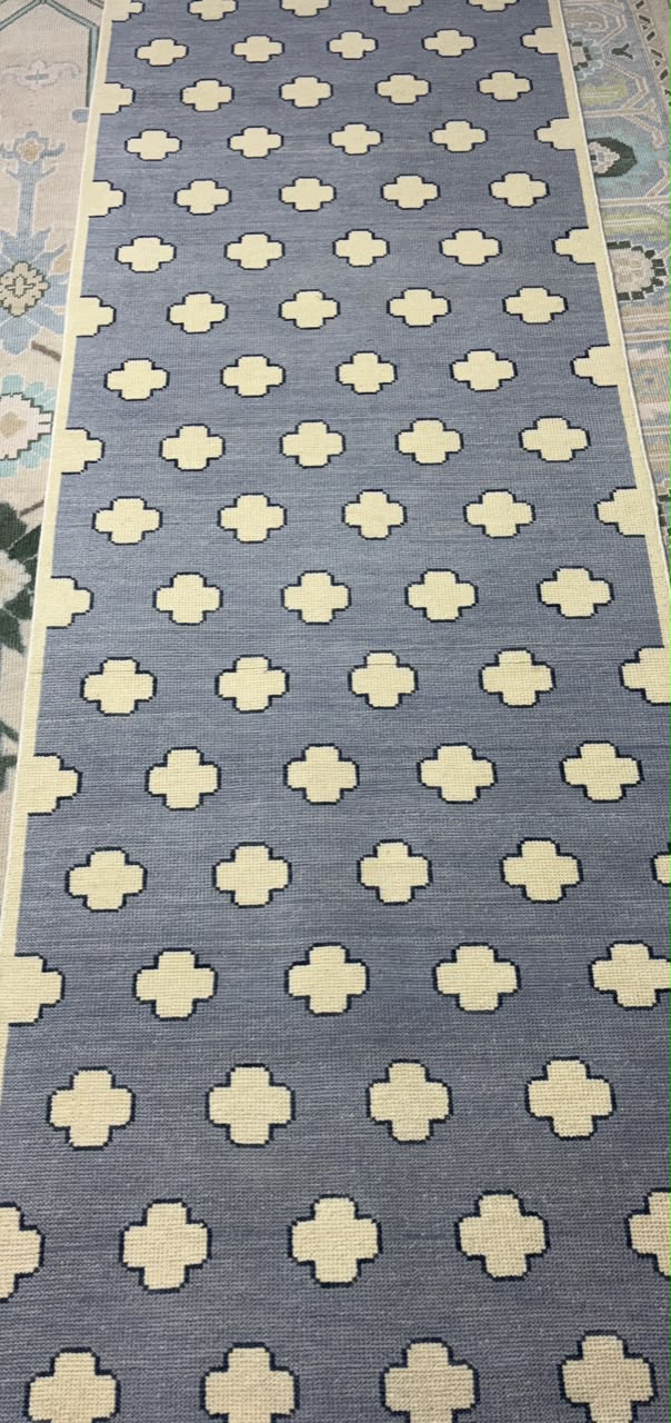 Handmade Scandinavian wool rug with a dusty blue background and ivory geometric quatrefoil pattern.