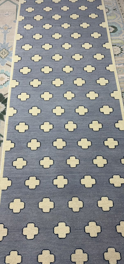 Handmade Scandinavian wool rug with a dusty blue background and ivory geometric quatrefoil pattern.