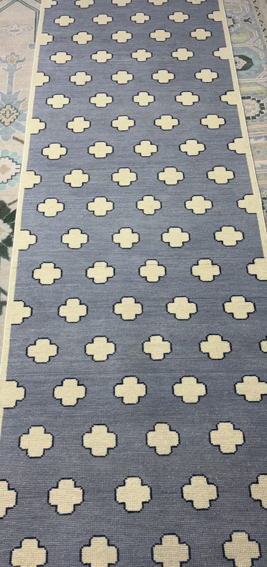Handmade Scandinavian wool rug with a dusty blue background and ivory geometric quatrefoil pattern.