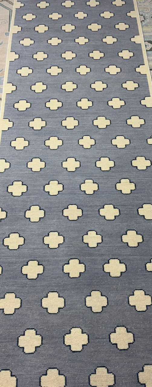 Full view of a handmade contemporary wool rug with an ivory geometric pattern on a dusty blue field.