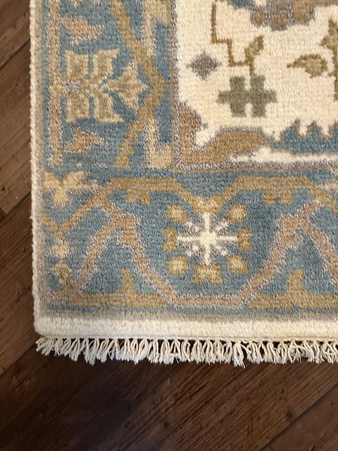 Corner detail of handmade tribal rug showing geometric border and animal motifs