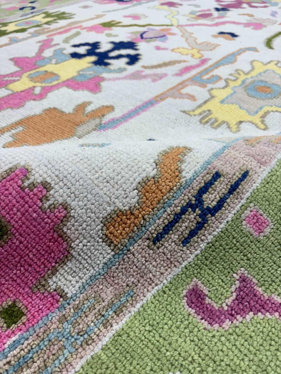 Close-up texture of handmade floral wool rug with pastel pink, blue, and yellow motifs