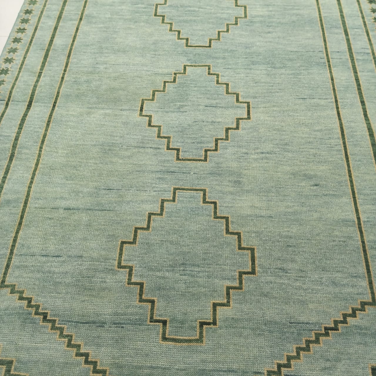 Minimal diamond pattern woven into sage green wool rug