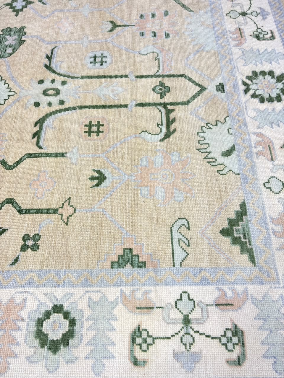 Sage green floral wool rug showing traditional botanical and geometric pattern