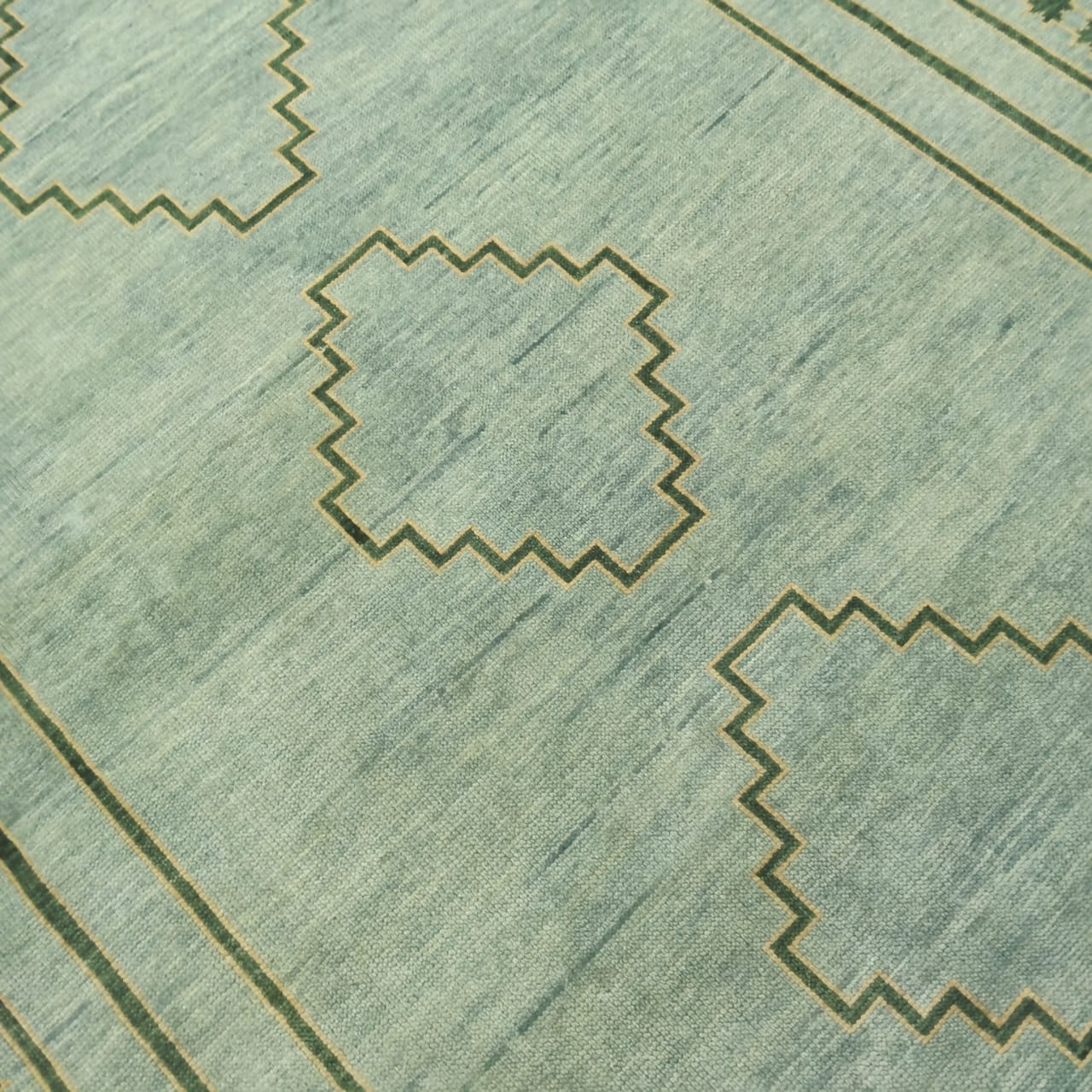 Angled view of minimalist sage green wool rug in full layout