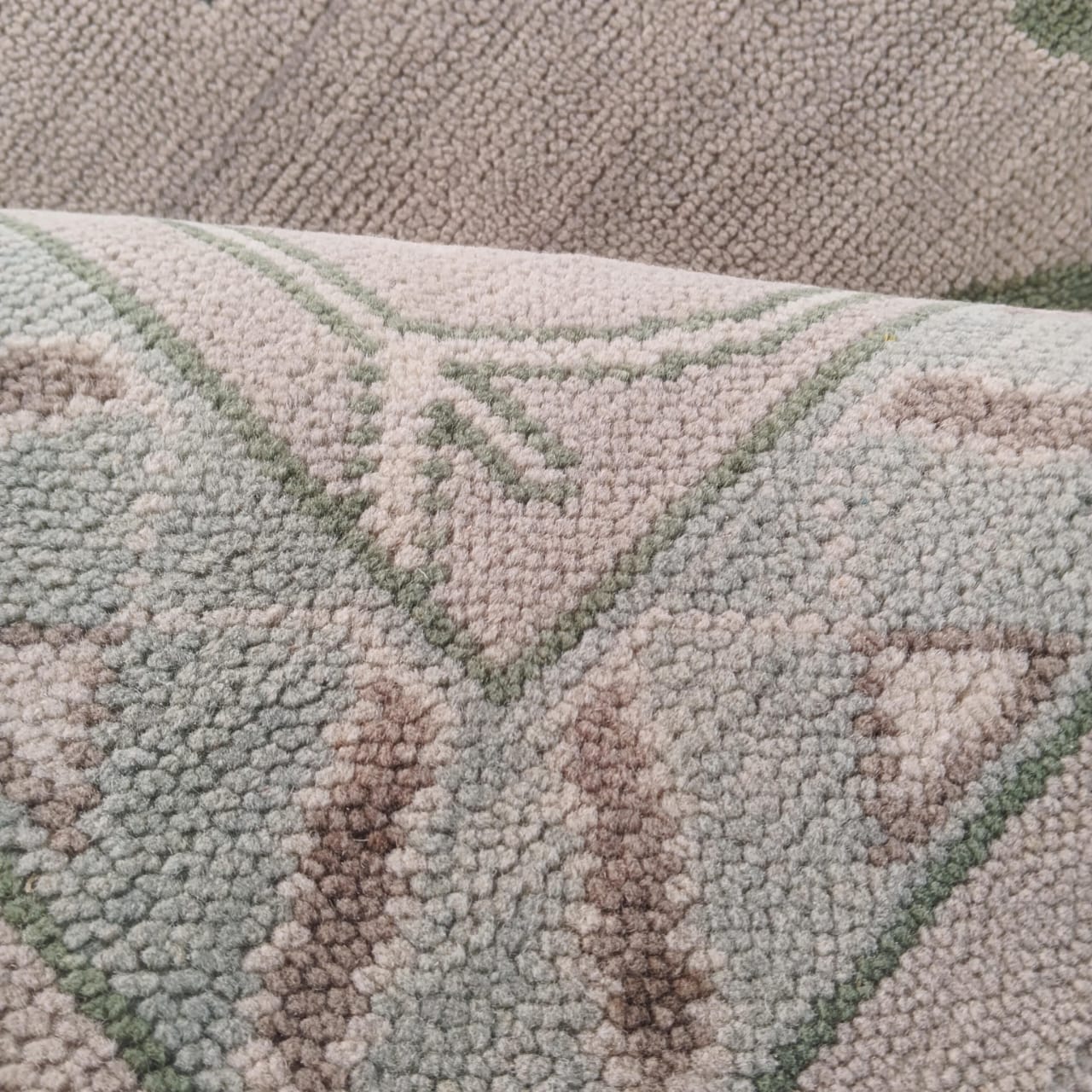 Close up of sage green and blue Oushak floral rug pattern