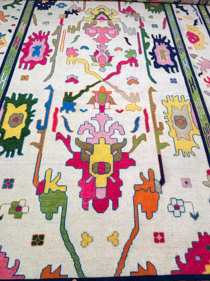 Full view of a handmade Nordic folk art wool rug with colorful abstract motifs and decorative green border.