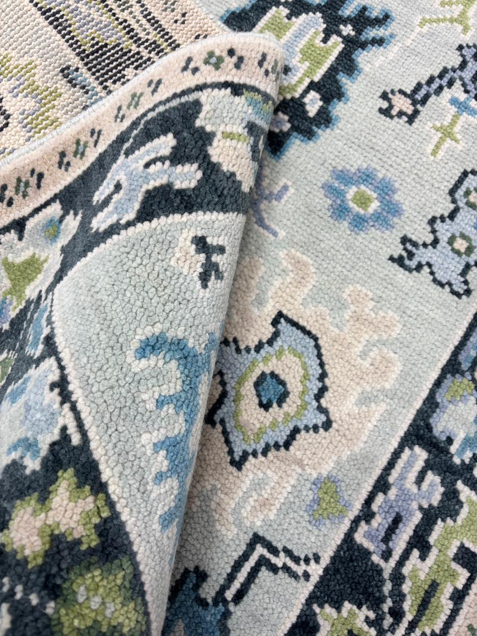 Close-up of premium wool texture with Scandinavian geometric folk motifs in ice blue, charcoal and sage green.