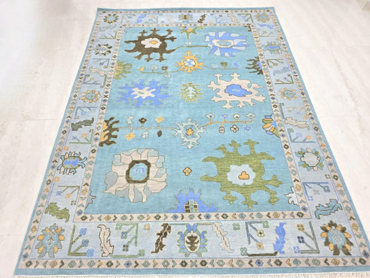 Sky blue Oushak hand tufted area rug with colorful floral motifs and ivory border