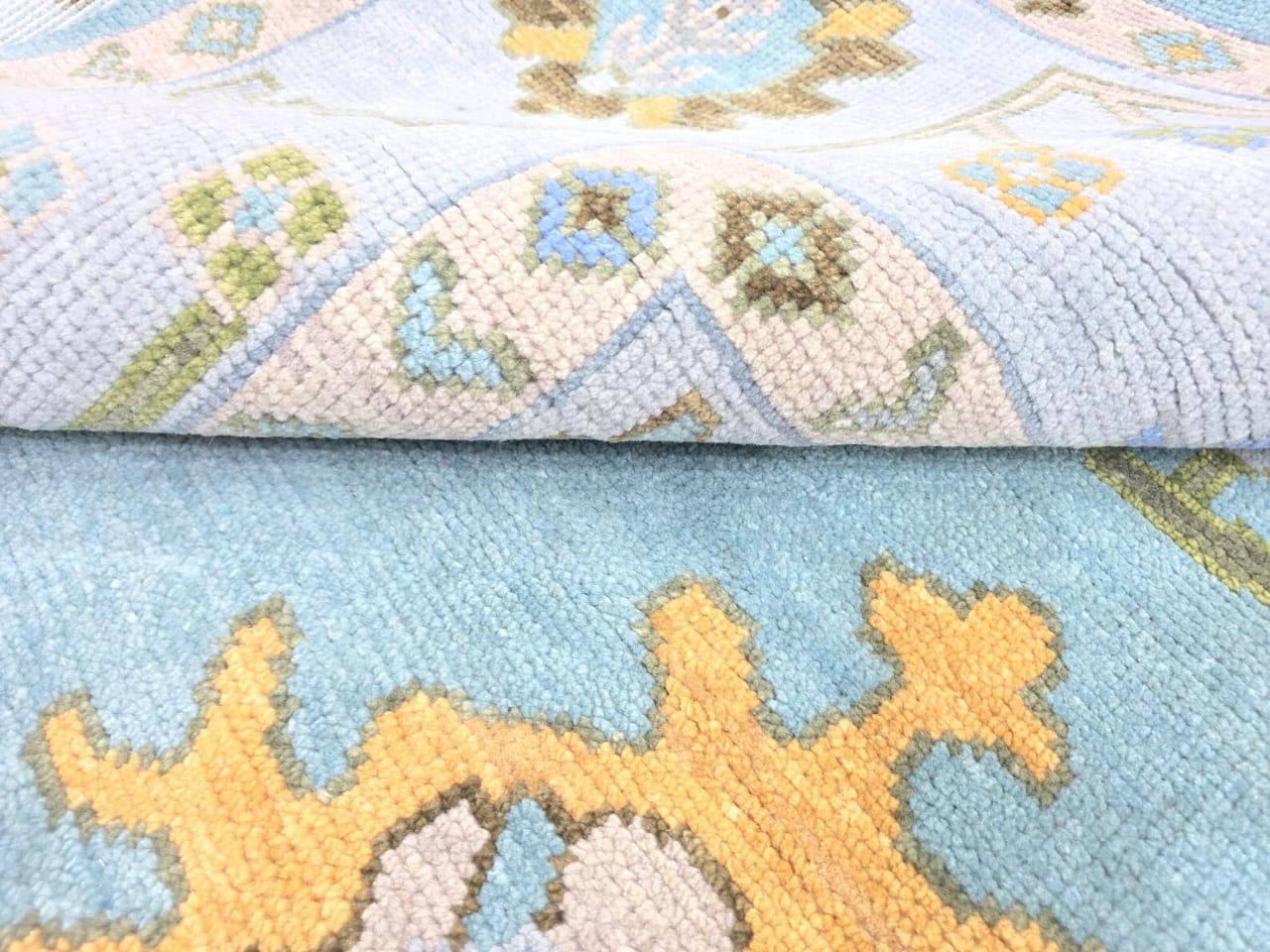 Close up of sky blue Oushak rug  with geometric and floral details