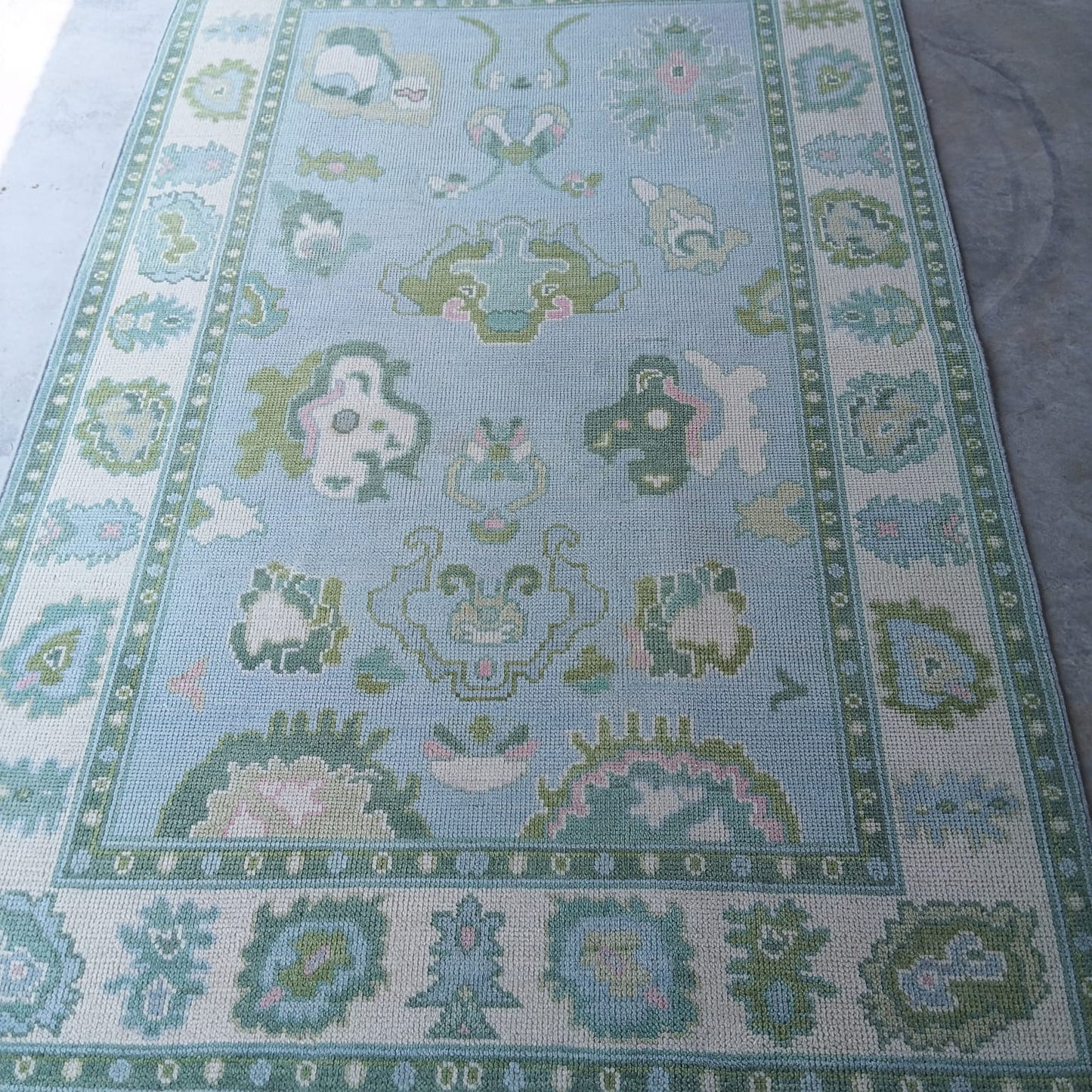 Handwoven sky blue and sage green Oushak wool rug with traditional Turkish floral border design